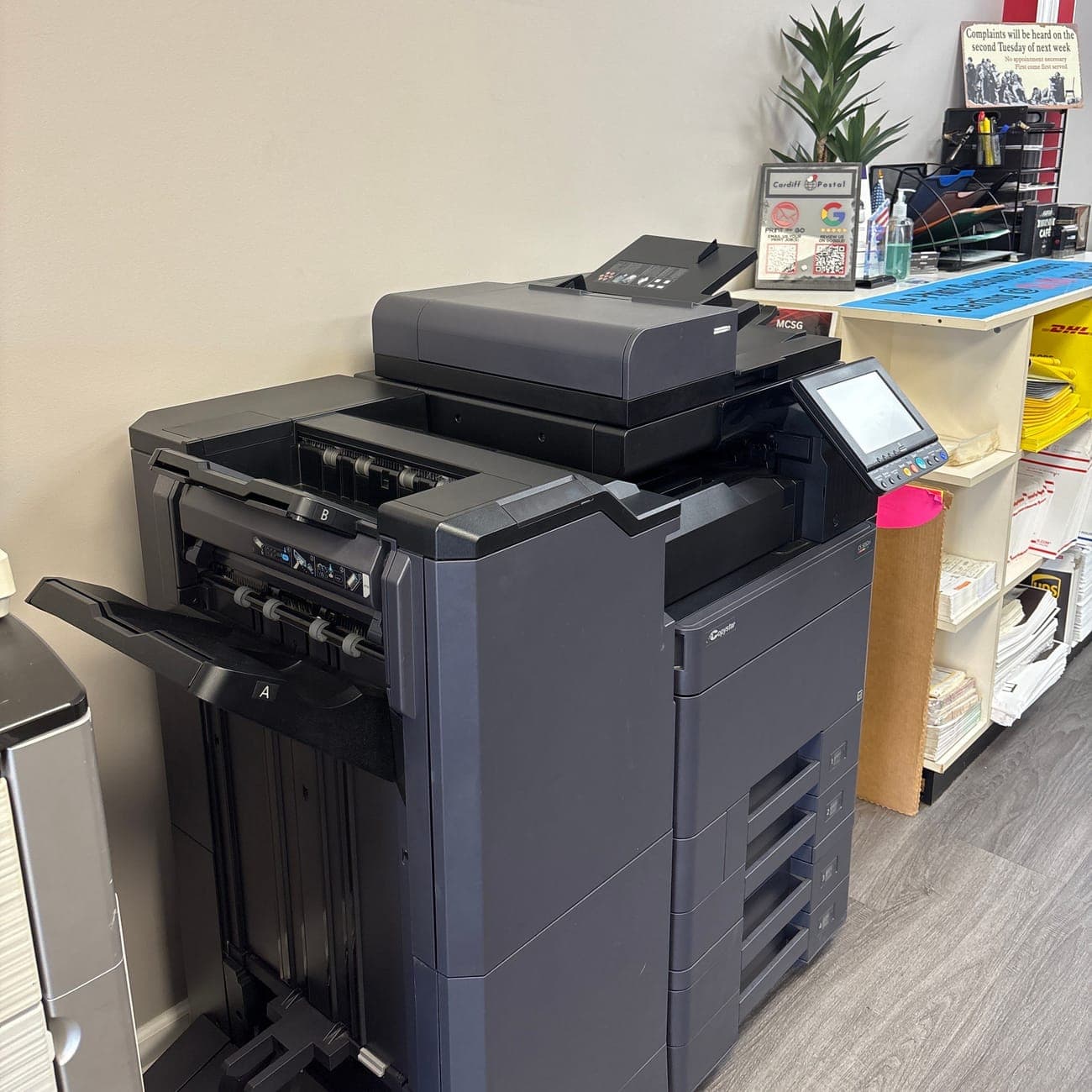 A large production copier with a finisher inside the store
