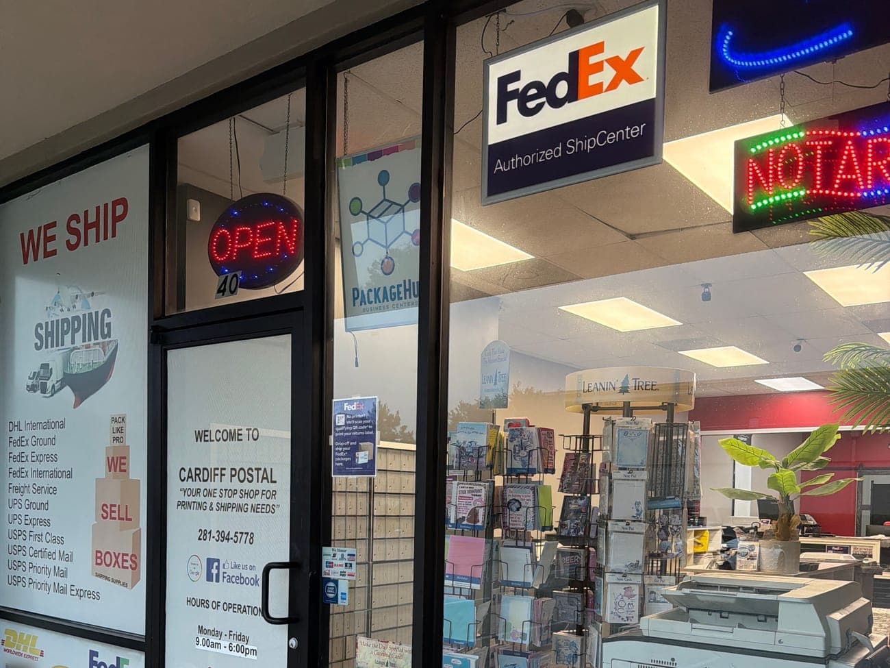 The Cardiff Postal glass front door at Suite 40 with an Open sign, a NOTARY neon sign and a FedEx Authorized ShipCenter sign