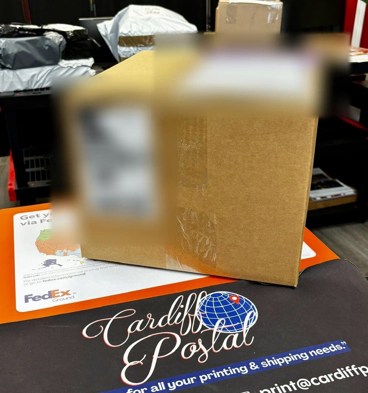 A packed cardboard box on the counter with its international shipping label and customs pouch blurred