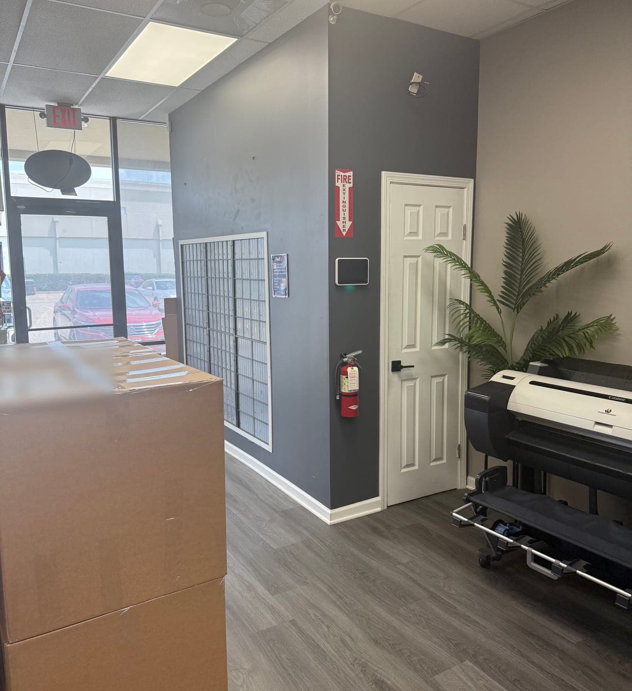The inside of the store near the entrance, with mailboxes on the wall and a wide-format printer