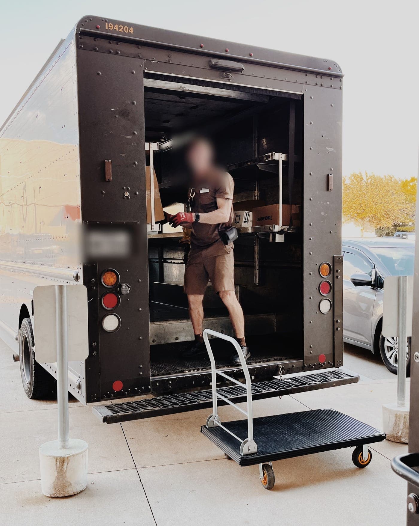 A UPS driver loading packages into the back of a UPS truck outside the store
