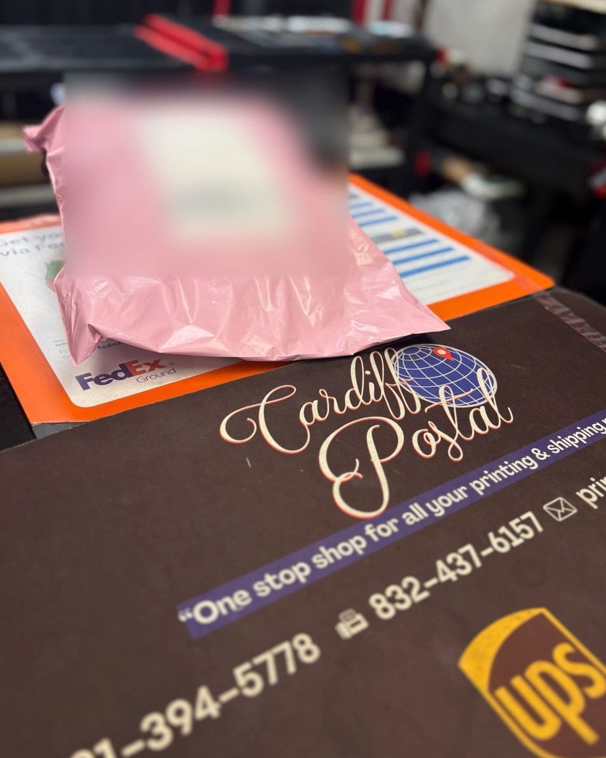 A pink USPS parcel on the Cardiff Postal counter mat (the address label is blurred)