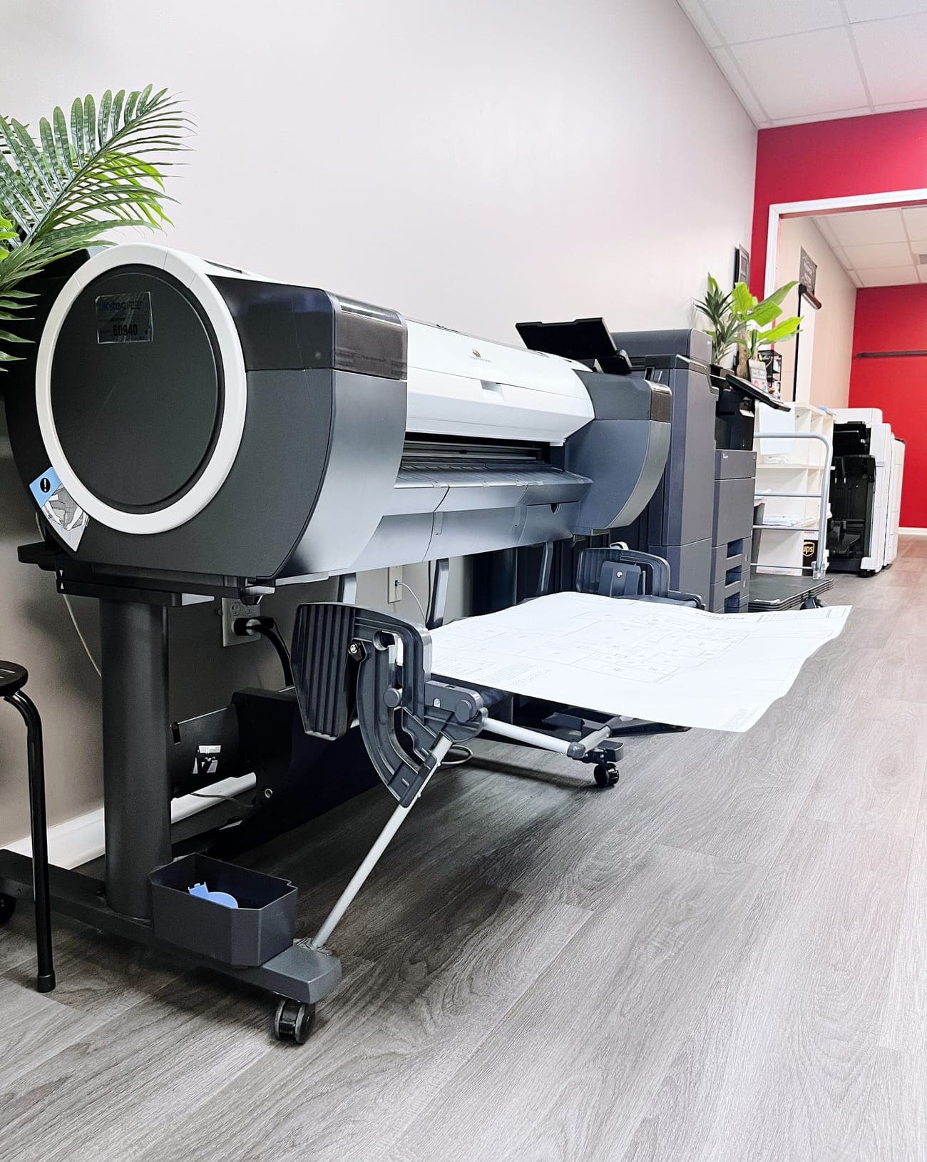 A wide-format printer in the store with a large sheet coming out of it